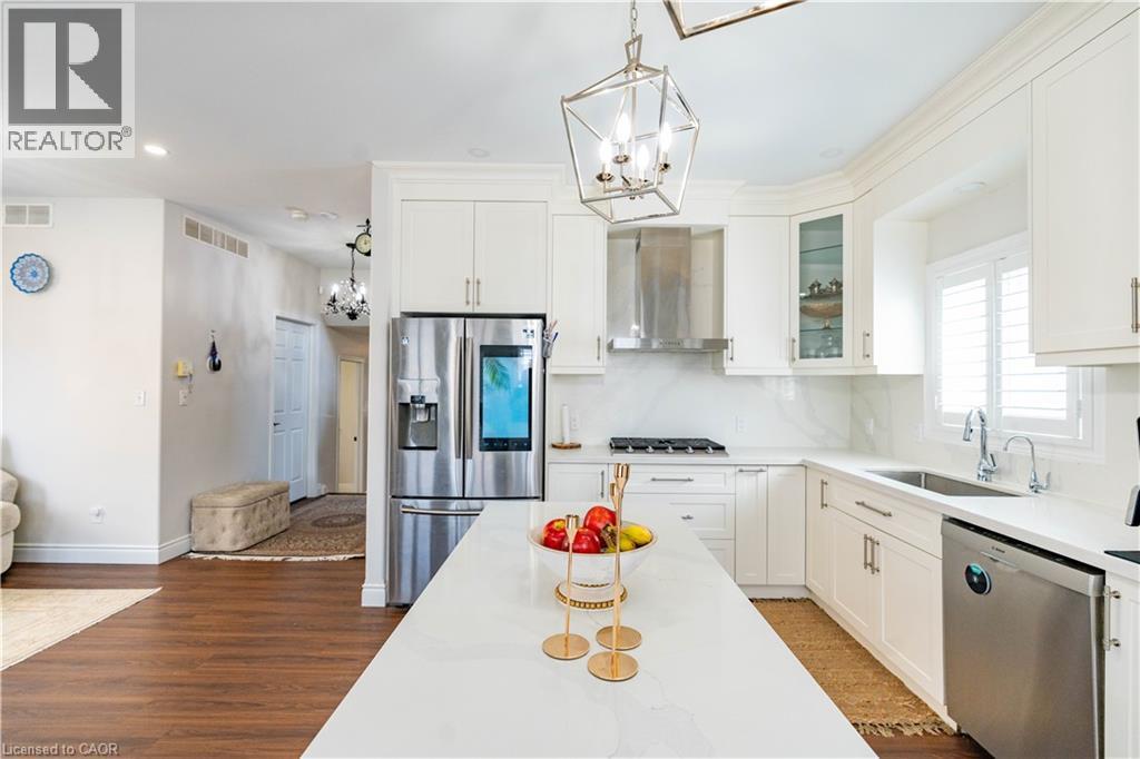 Gourmet kitchen featuring a central island, stainless steel appliances, white cabinetry, and wood-finish flooring - 122 Iron Gate Street, Kitchener, ON - Indoor Photo Showing Kitchen With Stainless Steel Kitchen With Upgraded Kitchen