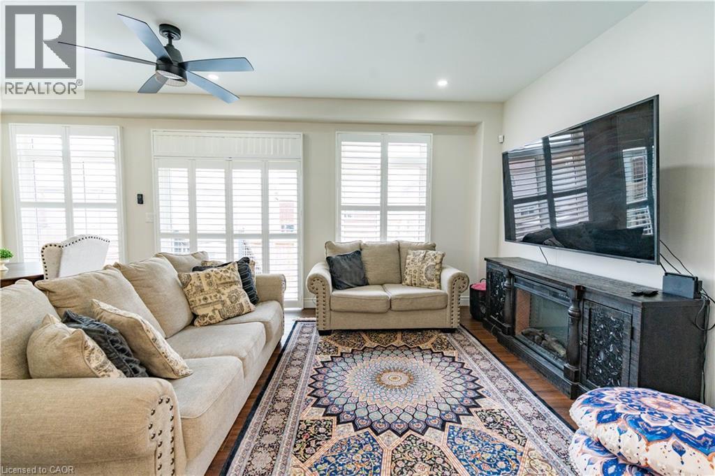 Recessed lighting, wood-finish flooring, white plantation shutters, and a ceiling fan with integrated lighting - 122 Iron Gate Street, Kitchener, ON - Indoor Photo Showing Living Room With Fireplace