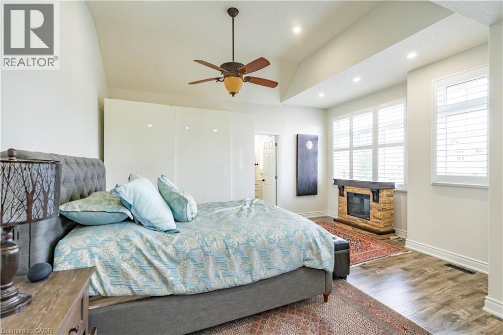 Vaulted ceiling, ceiling fan, recessed lighting, wood-finish flooring, and stone-clad fireplace - 122 Iron Gate Street, Kitchener, ON - Indoor Photo Showing Bedroom