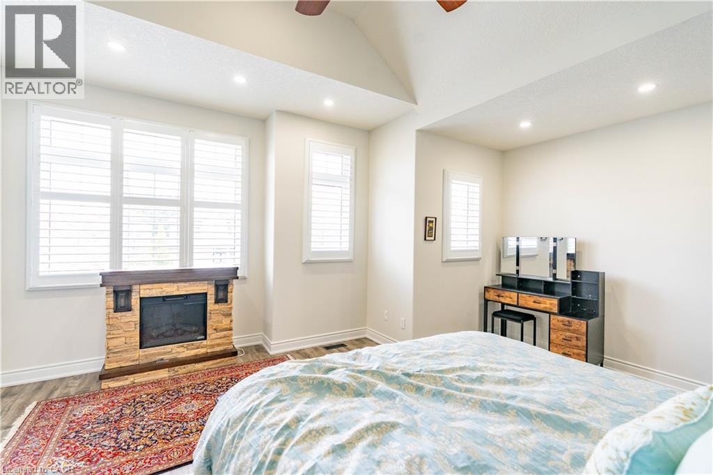 Vaulted ceiling with recessed lighting, stone-clad fireplace, wood-finish flooring, and multiple windows with plantation shutters - 122 Iron Gate Street, Kitchener, ON - Indoor Photo Showing Bedroom