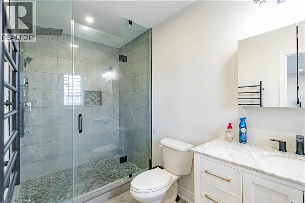 Glass-enclosed shower with pebble-finish flooring, built-in shelving, and a rain shower head - 122 Iron Gate Street, Kitchener, ON - Indoor Photo Showing Bathroom