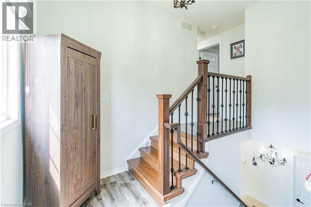 Wood-finish flooring, hardwood staircase with wrought iron spindles, and chandelier - 122 Iron Gate Street, Kitchener, ON - Indoor Photo Showing Other Room