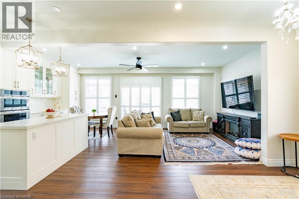 Open-concept living area with wood-finish flooring, white cabinetry, integrated double ovens, and recessed lighting - 122 Iron Gate Street, Kitchener, ON - Indoor