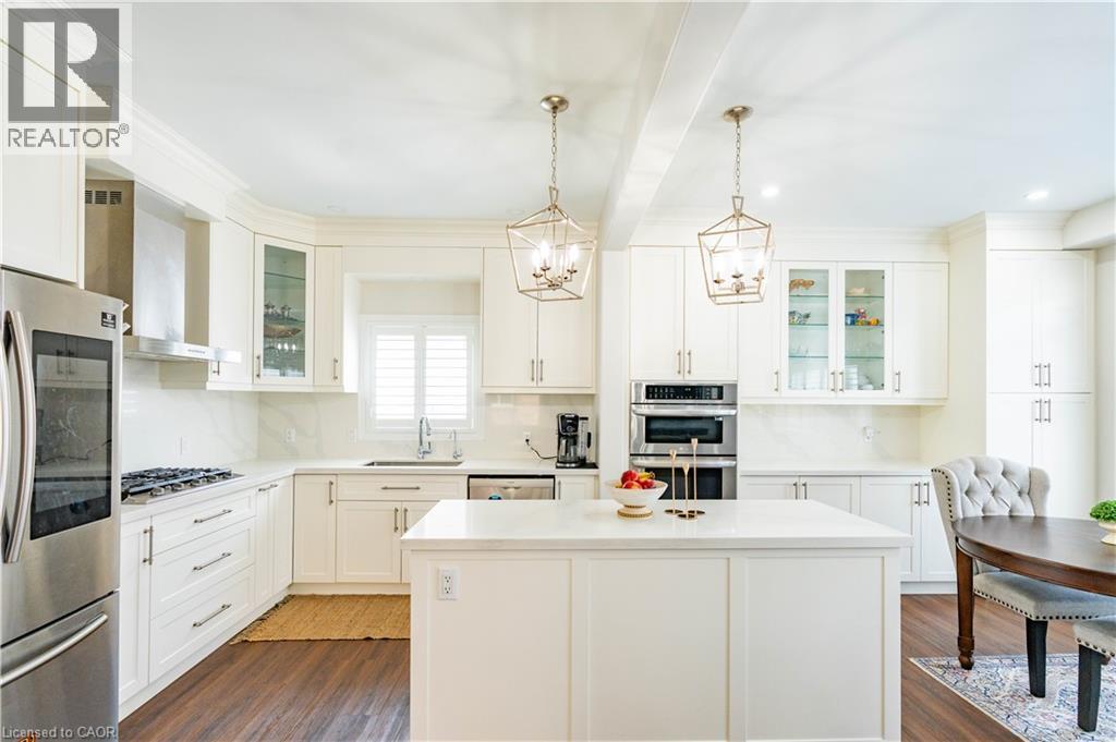White cabinetry with glass-front accents, stainless steel appliances, solid surface countertops, and wood-finish flooring - 122 Iron Gate Street, Kitchener, ON - Indoor Photo Showing Kitchen With Upgraded Kitchen