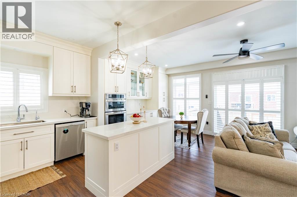 Kitchen featuring white cabinetry, stainless steel appliances, a center island, and wood-finish flooring - 122 Iron Gate Street, Kitchener, ON - Indoor Photo Showing Other Room