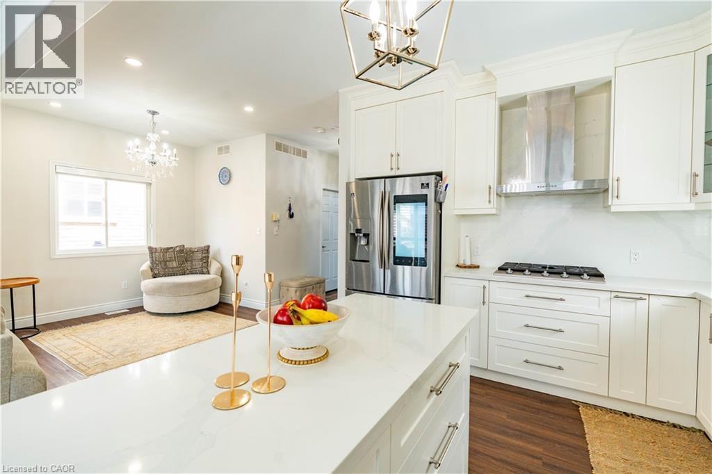 White shaker cabinetry, stainless steel appliances, a kitchen island with stone countertop, wood-finish flooring, and recessed lighting - 122 Iron Gate Street, Kitchener, ON - Indoor Photo Showing Kitchen With Upgraded Kitchen