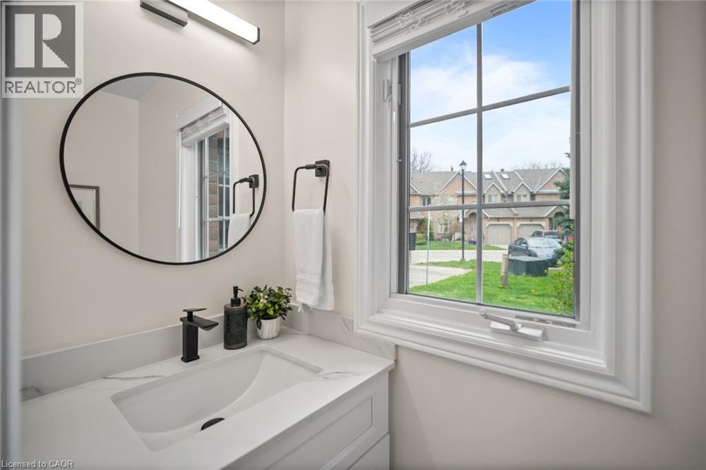 White cabinetry with integrated sink, black matte faucet, and round framed mirror - 320 Hamilton Drive Unit# 10, Ancaster, ON - Indoor Photo Showing Bathroom