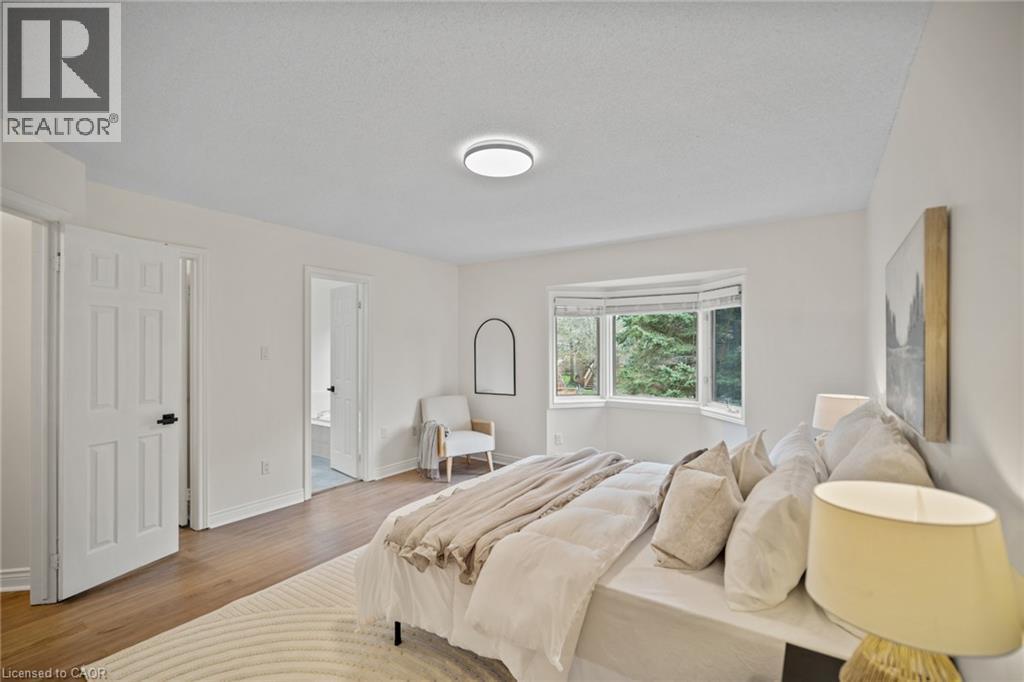 Recessed lighting, wood-finish flooring, white paneled doors with black hardware, and a bay window - 320 Hamilton Drive Unit# 10, Ancaster, ON - Indoor Photo Showing Bedroom