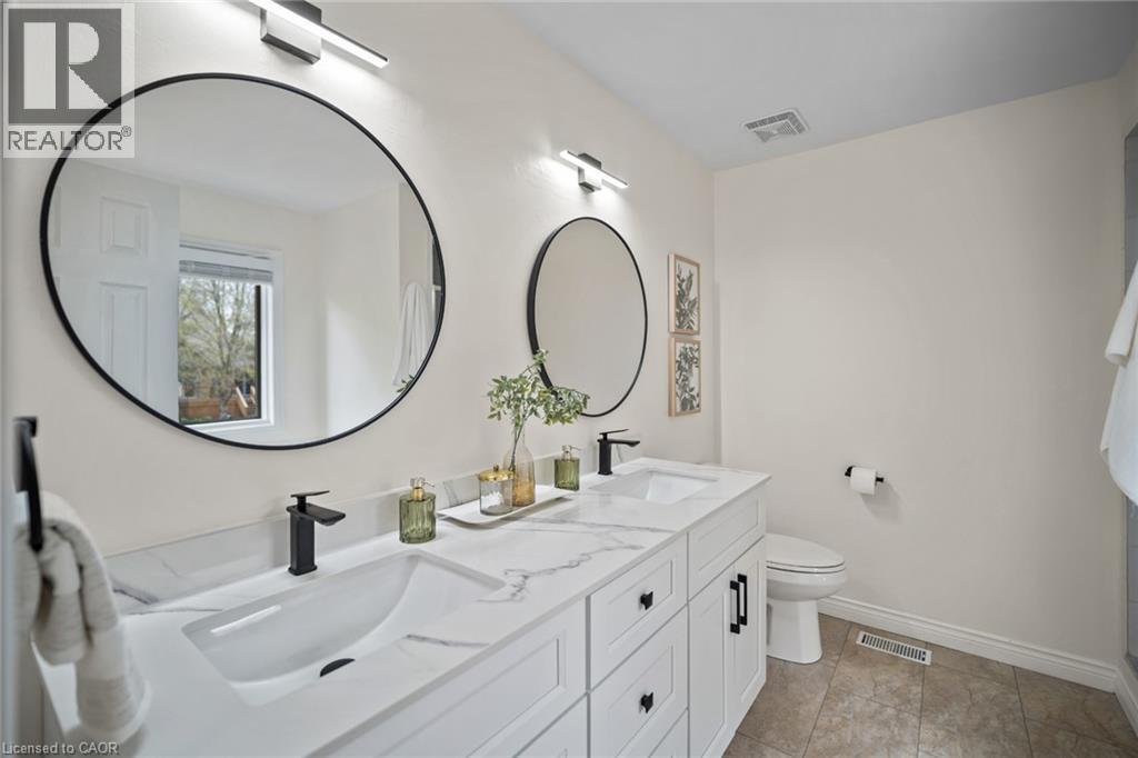 Double vanity with integrated sinks, black finish faucets, and white shaker-style cabinetry - 320 Hamilton Drive Unit# 10, Ancaster, ON - Indoor Photo Showing Bathroom