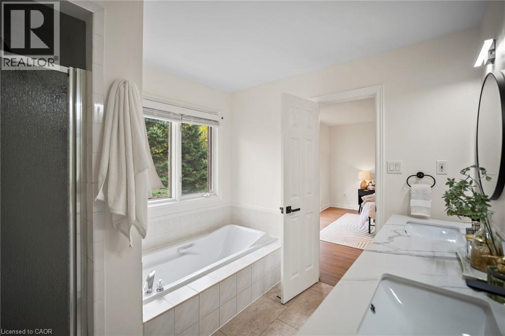 Dual vanity with integrated sinks, built-in soaking tub, separate shower enclosure, and tiled flooring - 320 Hamilton Drive Unit# 10, Ancaster, ON - Indoor Photo Showing Bathroom