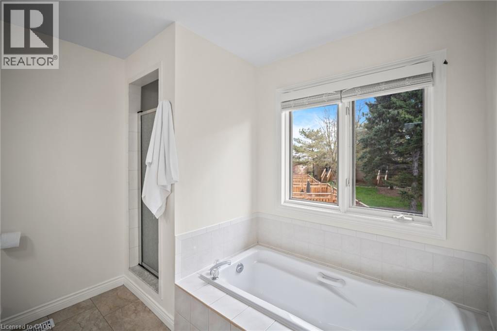Bathtub with tiled surround, shower enclosure, and a large window - 320 Hamilton Drive Unit# 10, Ancaster, ON - Indoor Photo Showing Bathroom