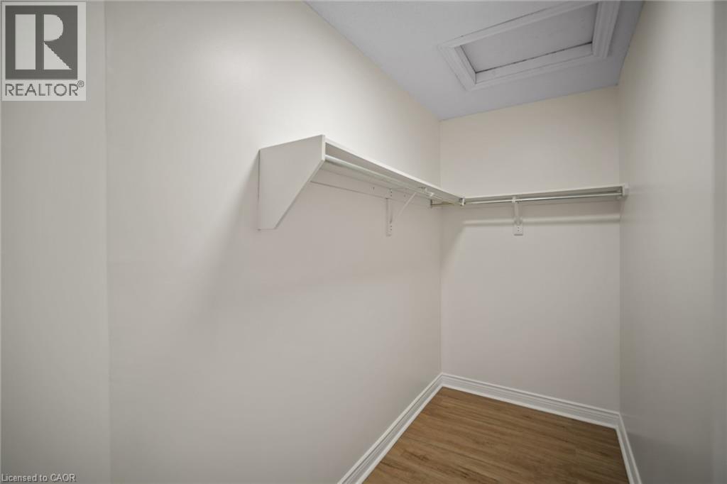 Walk-in closet with wood-finish flooring, white walls, built-in shelving, and hanging rods - 320 Hamilton Drive Unit# 10, Ancaster, ON - Indoor With Storage