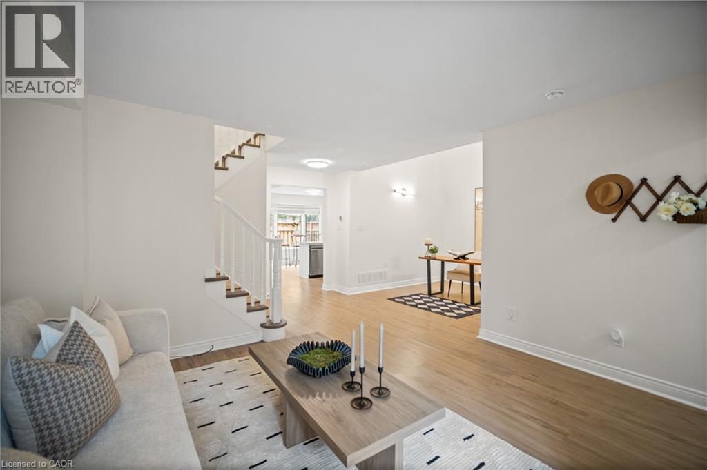 Open-concept living space featuring wood-finish flooring, a white spindle staircase, and recessed lighting - 320 Hamilton Drive Unit# 10, Ancaster, ON - Indoor