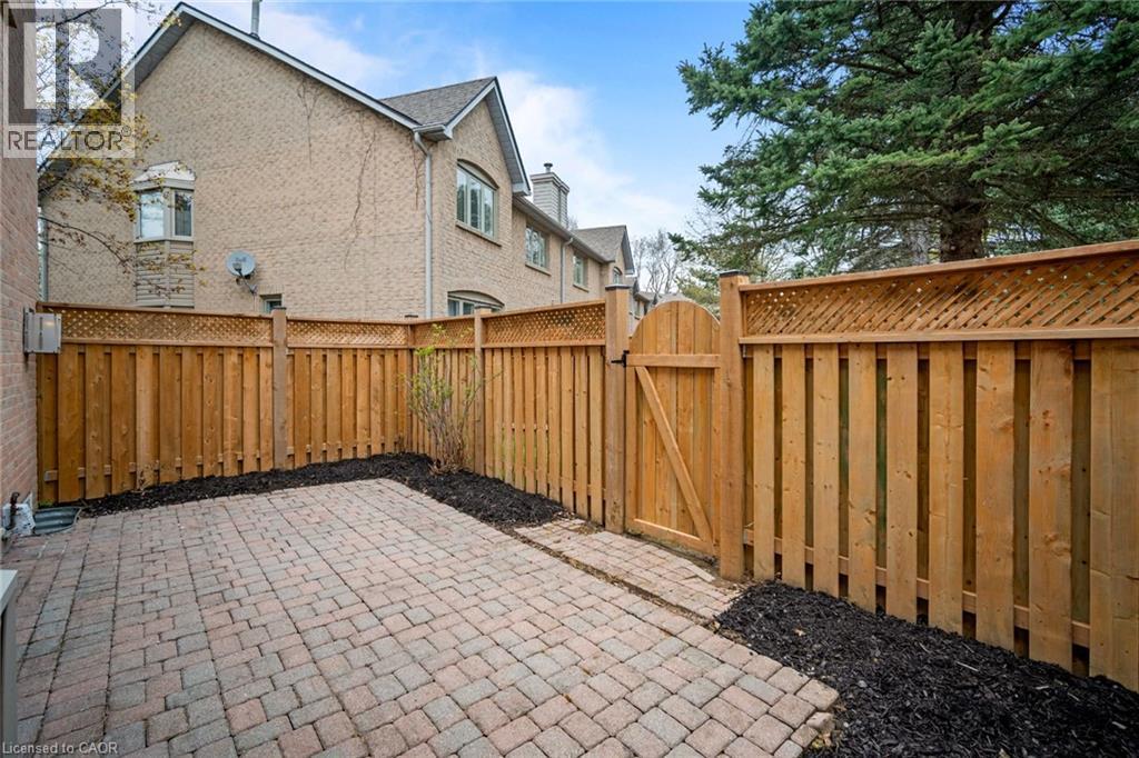 Paved patio with brick pavers, wood privacy fencing with lattice top, and a wood gate - 320 Hamilton Drive Unit# 10, Ancaster, ON - Outdoor With Exterior