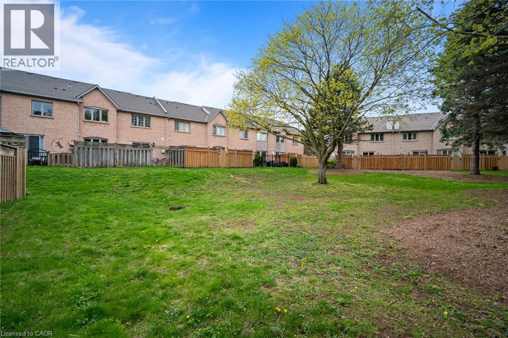 Expansive grassy area featuring mature trees and a wood fence border - 320 Hamilton Drive Unit# 10, Ancaster, ON - Outdoor With Backyard