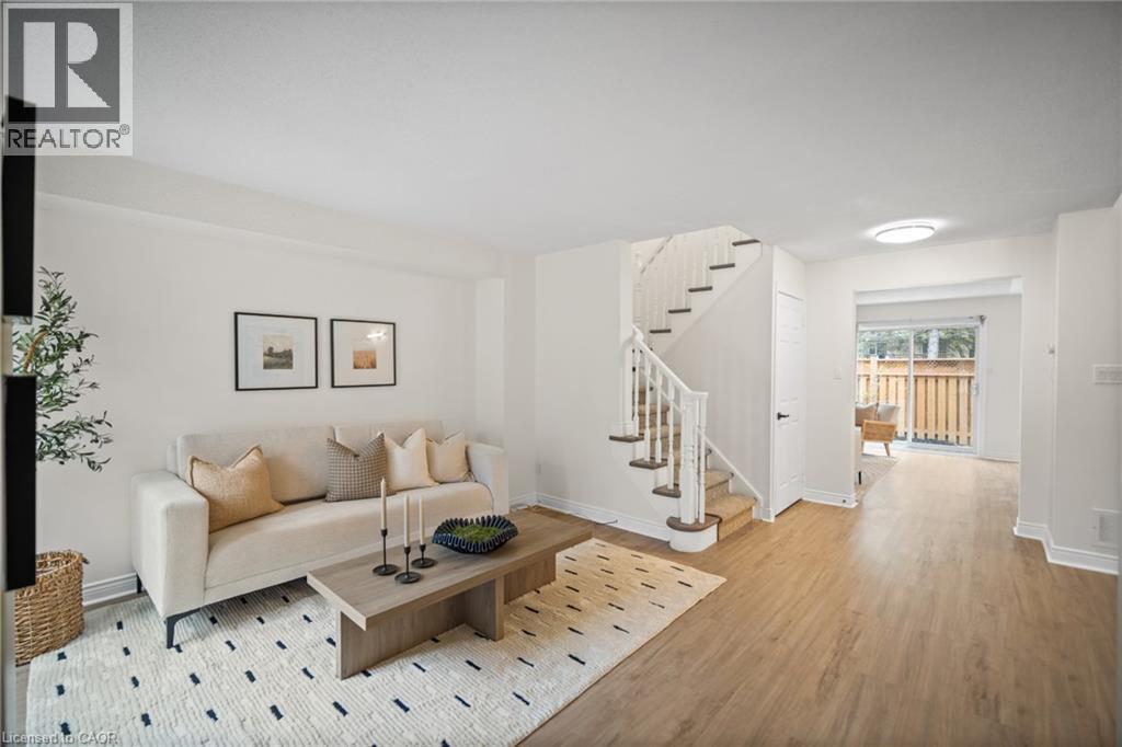 Light wood-finish flooring throughout, white painted walls, and a staircase with white risers and wood treads - 320 Hamilton Drive Unit# 10, Ancaster, ON - Indoor Photo Showing Living Room