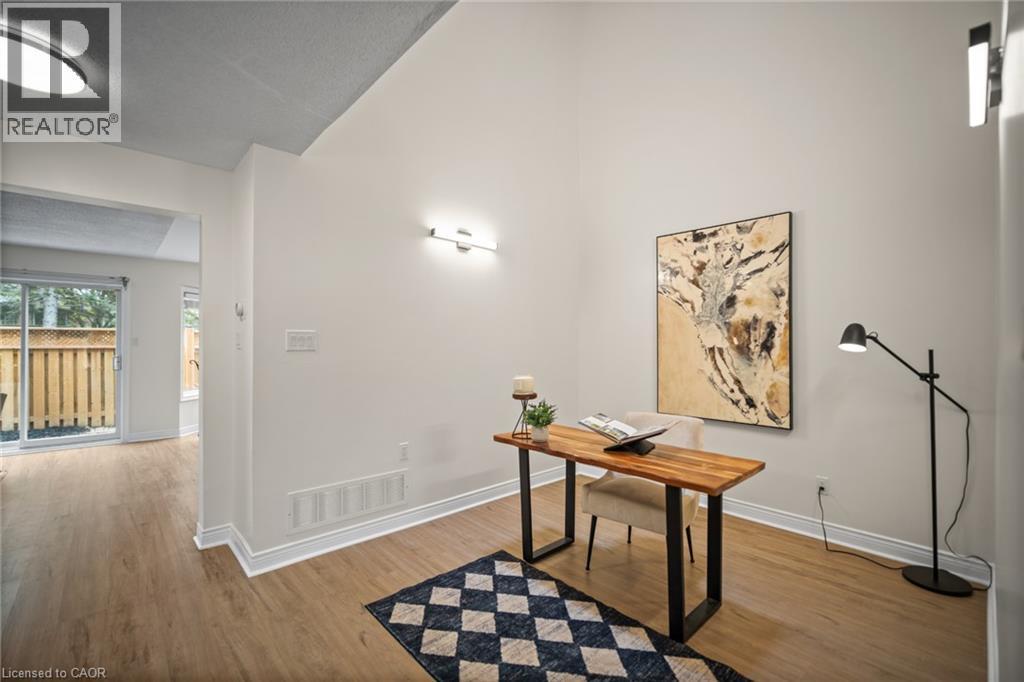 Vaulted ceiling, wood-finish flooring, sliding glass door, white walls, and a wall-mounted light fixture - 320 Hamilton Drive Unit# 10, Ancaster, ON - Indoor Photo Showing Office