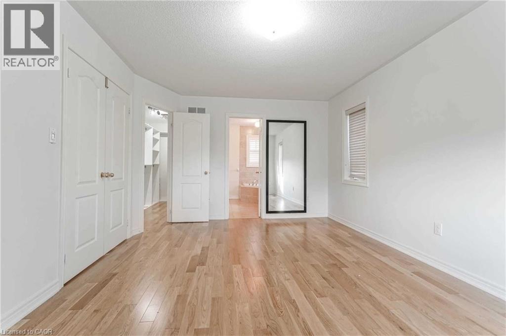 Unfurnished bedroom featuring light wood-type flooring, a textured ceiling, a walk in closet, and connected bathroom - 3 Coolwater Drive Unit# Upper, Brampton, ON - Indoor Photo Showing Other Room