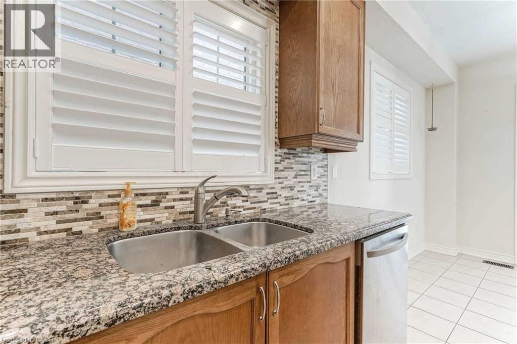 Kitchen featuring stainless steel dishwasher, decorative backsplash, light tile patterned flooring, and stone countertops - 3 Coolwater Drive Unit# Upper, Brampton, ON - Indoor Photo Showing Kitchen With Double Sink