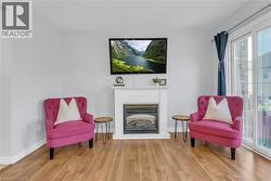 Wood-finish flooring, white fireplace with mantle, built-in fireplace, wall-mounted television, and sliding glass door - 