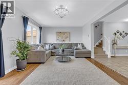 Hardwood-finish flooring, recessed lighting, chandelier, neutral paint, and staircase with white railing - 
