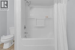 Bathtub with integrated shower, chrome fixtures, and a white shower curtain - 