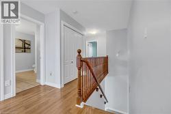 Wood-finish flooring, white trim, wood staircase with banister, and a bifold closet door - 