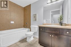 Porcelain bathtub with full-height tile surround, tile flooring, dark wood-finish vanity with countertop, oval undermount sink, and wall-mounted mirror - 