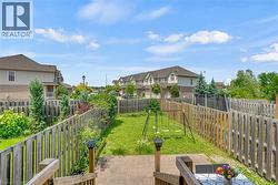 Expansive backyard featuring a manicured lawn, established wooden fencing, and mature perimeter landscaping - 