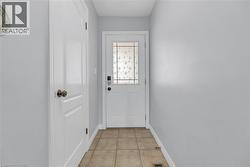Entryway featuring a white paneled door with patterned glass, a second white paneled door, light gray walls, and tile flooring - 