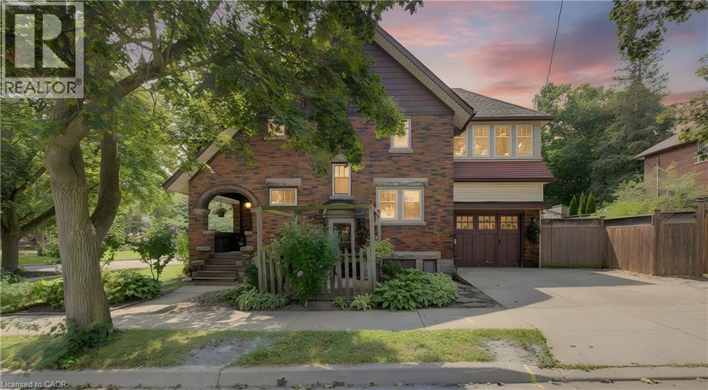 Brick facade residence featuring an arched stone entry, covered porch, and mature trees - 150 Union Boulevard, Kitchener, ON - Outdoor With Facade