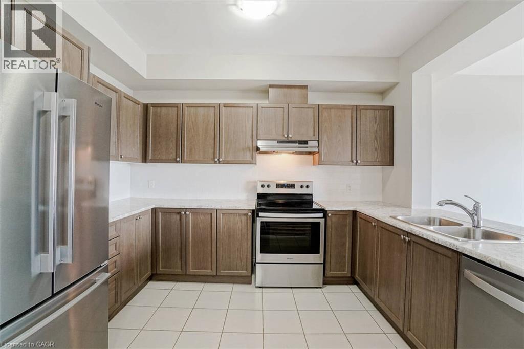 Kitchen with extensive wood-finish cabinetry, light-toned countertops, and stainless steel appliances - 70 Bradbury Road, Hamilton, ON - Indoor Photo Showing Kitchen With Stainless Steel Kitchen With Double Sink