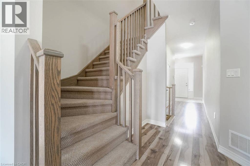 Staircase with wood-finish newel posts and handrails, carpeted treads, and light gray wall paint - 70 Bradbury Road, Hamilton, ON - Indoor Photo Showing Other Room