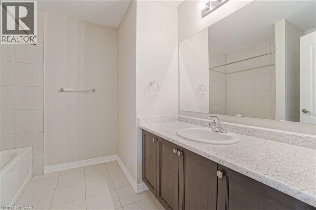 Integrated vanity with a solid surface countertop, undermount sink, and dark wood-finish cabinetry - 70 Bradbury Road, Hamilton, ON - Indoor Photo Showing Bathroom