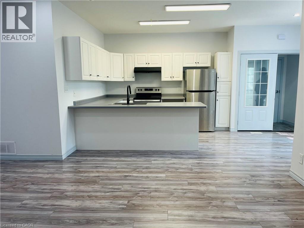 Kitchen featuring white cabinetry, stainless steel refrigerator, black range, and a breakfast bar - 83 Keewatin Avenue, Kitchener, ON - Indoor Photo Showing Kitchen With Double Sink