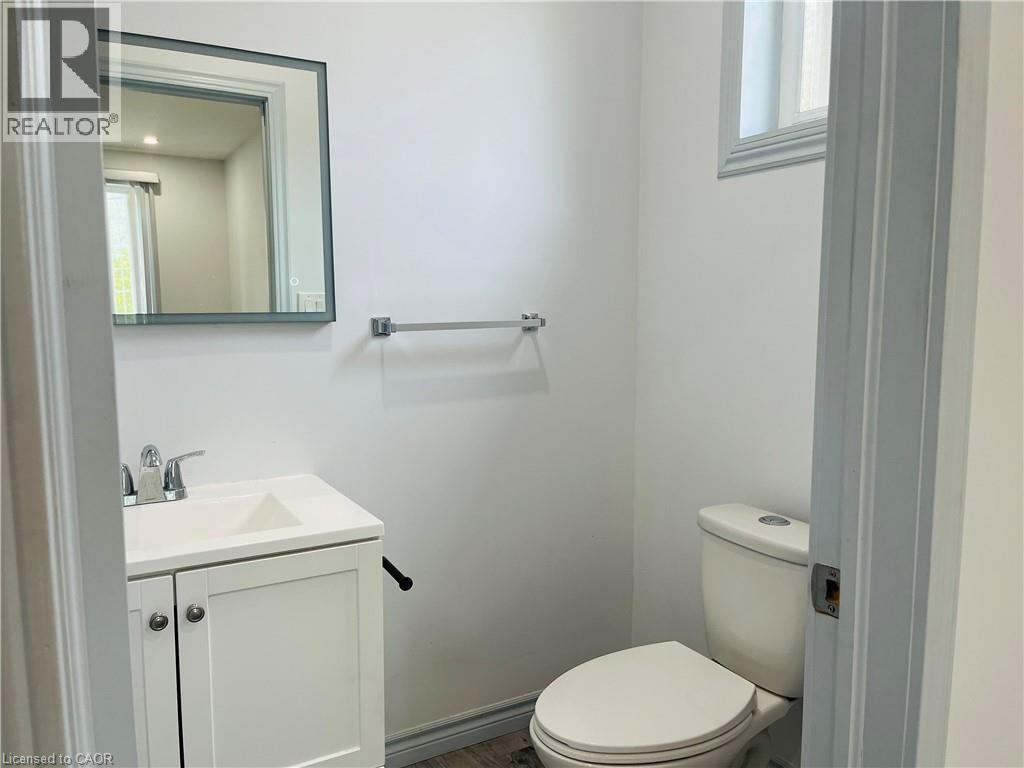 White vanity with integrated sink, chrome faucet, framed mirror, and window with trim - 83 Keewatin Avenue, Kitchener, ON - Indoor Photo Showing Bathroom