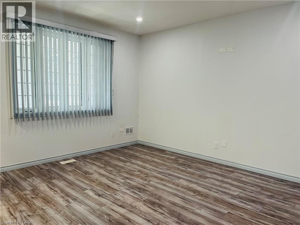 Room featuring wood-finish flooring, white walls, and a window with vertical blinds - 83 Keewatin Avenue, Kitchener, ON - Indoor Photo Showing Other Room