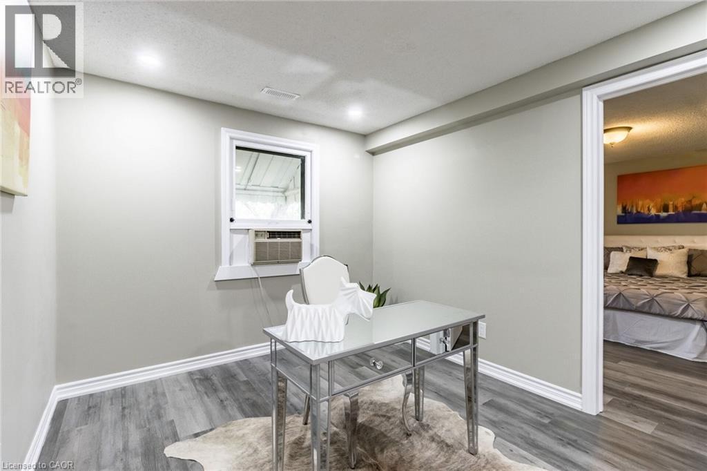 Recessed ceiling lighting, window with white trim, wall-mounted air conditioning unit, light grey wall paint, and wood-finish flooring - 15 Spiers Crescent, Cambridge, ON - Indoor Photo Showing Other Room