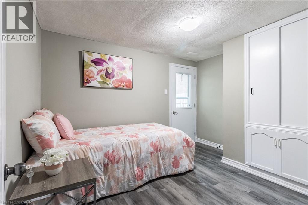 Wood-finish flooring, built-in white cabinetry with decorative trim, white paneled door with glass insert, and flush-mount ceiling light - 15 Spiers Crescent, Cambridge, ON - Indoor Photo Showing Bedroom