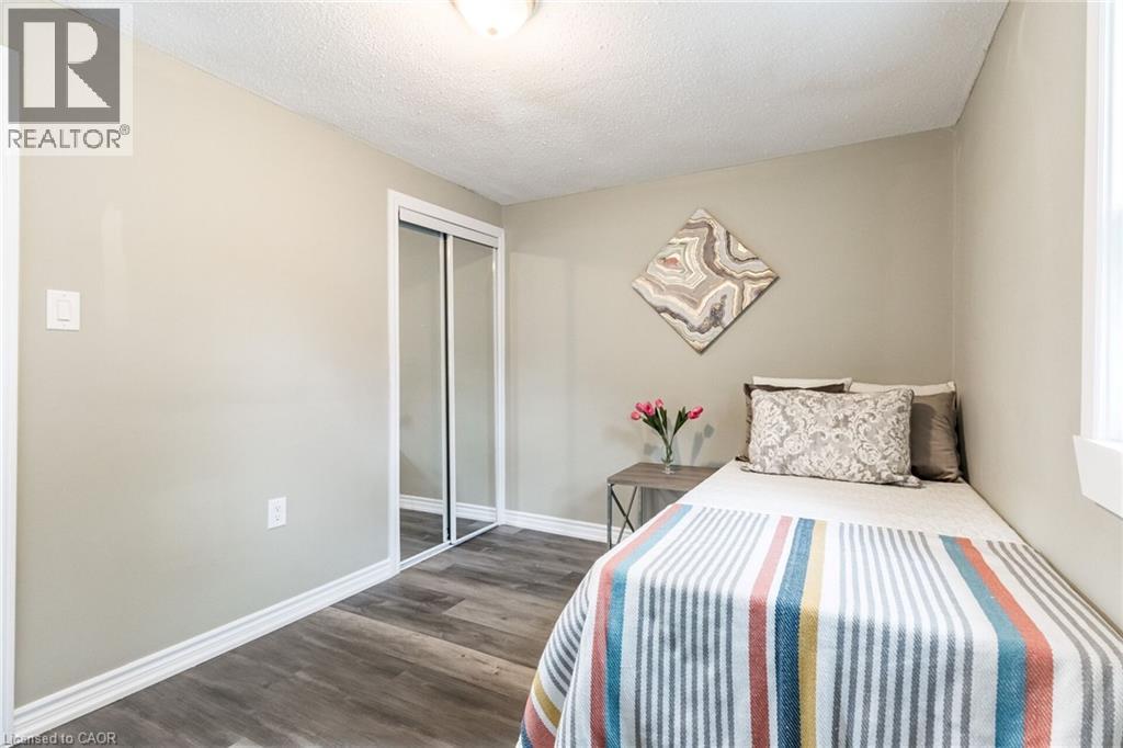 Wood-finish flooring, mirrored sliding closet doors, and a window with white trim - 15 Spiers Crescent, Cambridge, ON - Indoor Photo Showing Bedroom