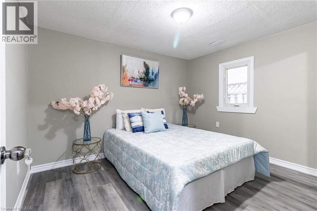 Light-toned walls, wood-finish flooring, white window trim, and a ceiling-mounted light fixture - 15 Spiers Crescent, Cambridge, ON - Indoor Photo Showing Bedroom