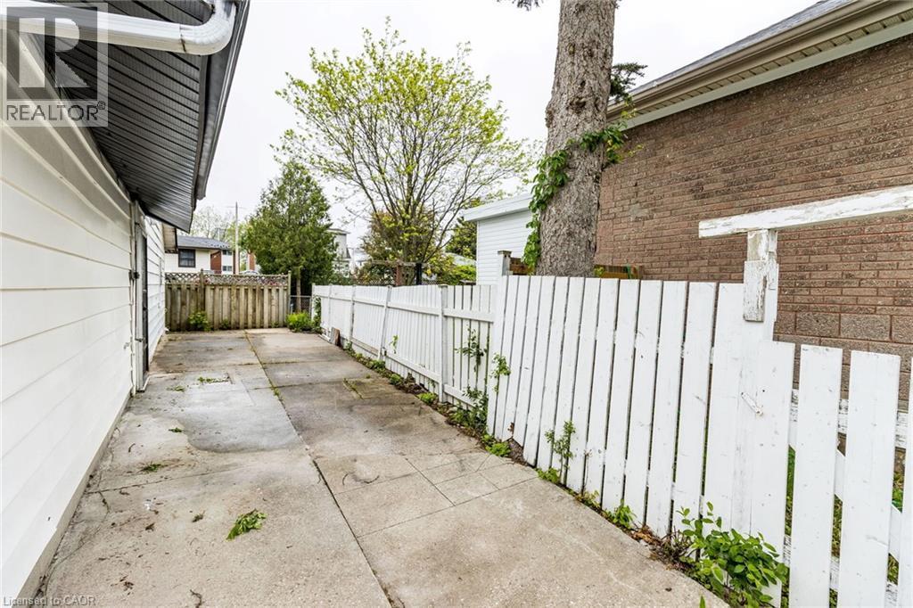 Paved side yard with a white picket fence and wood privacy fence - 15 Spiers Crescent, Cambridge, ON - Outdoor With Exterior