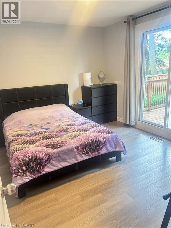 Wood-finish flooring, sliding glass door, private deck, and a contemporary dark wood-finish dresser - 510 Oakridge Place, Waterloo, ON - Indoor Photo Showing Bedroom