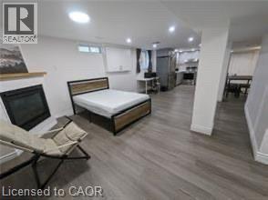 Wood-finish flooring throughout, fireplace with a wood mantle, recessed lighting, and kitchen area with stainless steel appliances - 510 Oakridge Place, Waterloo, ON - Indoor