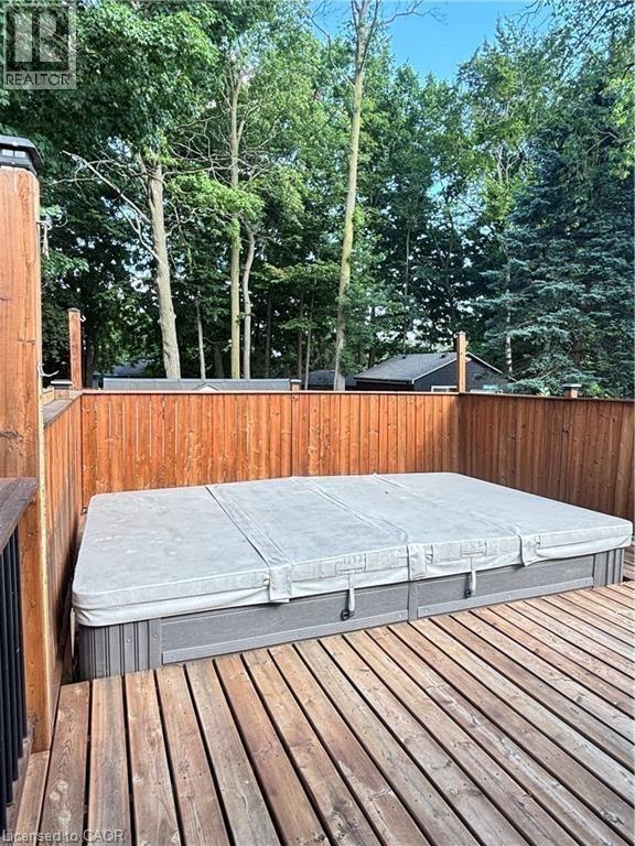 Expansive deck featuring a hot tub, wood privacy fencing, and mature trees - 510 Oakridge Place, Waterloo, ON - Outdoor With Deck Patio Veranda