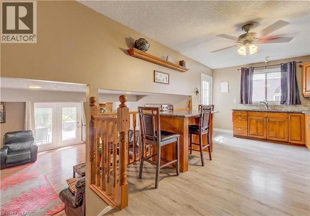 Open-concept living space featuring wood-finish flooring, a kitchen island with seating, wood cabinetry, a ceiling fan, and French doors leading to exterior - 599 Coldstream Drive, Waterloo, ON - Indoor Photo Showing Dining Room