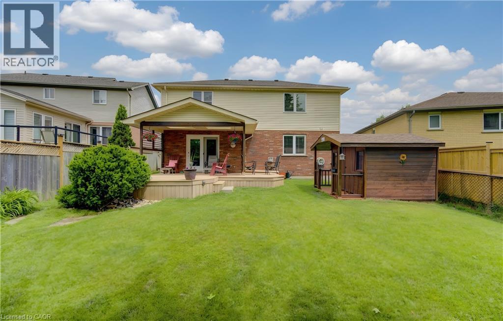 Expansive green lawn with a multi-level wood deck featuring a covered patio - 599 Coldstream Drive, Waterloo, ON - Outdoor With Deck Patio Veranda