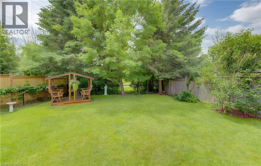 Expansive backyard featuring a manicured lawn, established trees, and a wooden gazebo structure - 599 Coldstream Drive, Waterloo, ON - Outdoor With Backyard