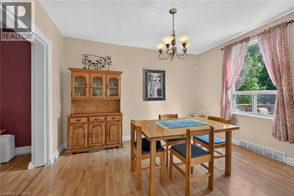 Wood-finish flooring throughout, featuring a multi-pane window with white trim, and a brass-tone ceiling fixture - 230 Picton Street E, Hamilton, ON - Indoor Photo Showing Dining Room