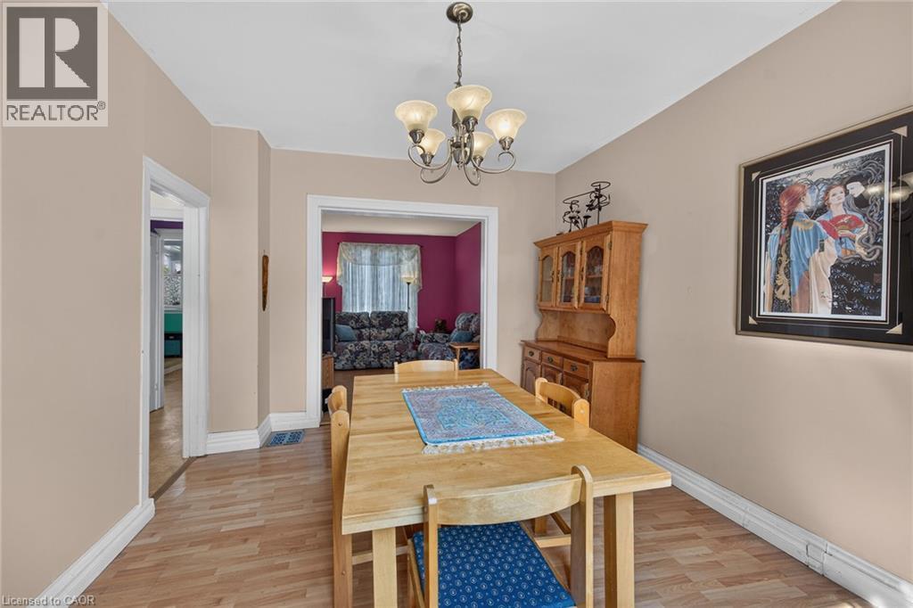 Dining area with wood-finish flooring, a decorative chandelier, and neutral wall tones - 230 Picton Street E, Hamilton, ON - Indoor Photo Showing Dining Room
